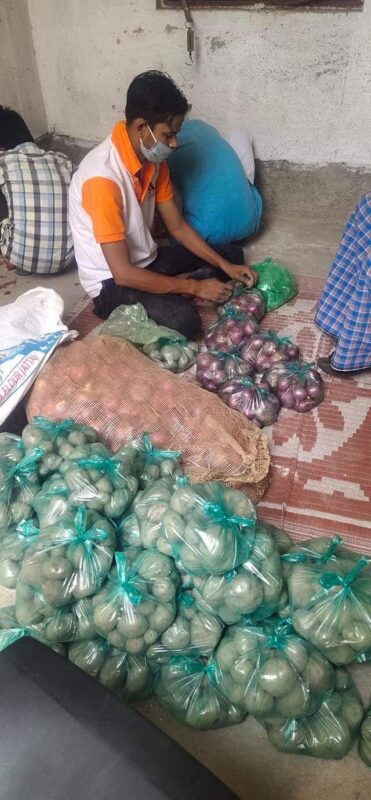 A volunteer sorting potatoes, onions and staples into individual family relief packs